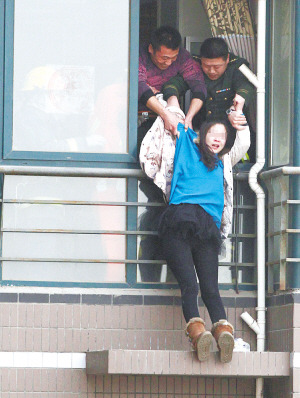 年輕女子在高樓窗外一小平臺坐了1個多小時后，被消防官兵拉進屋內。