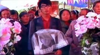 何濱捧著愛(ài)人遺像，送上深情一吻。（視頻截圖）