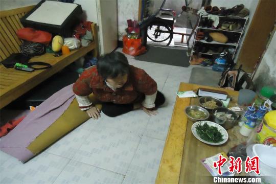 17日下午，56歲小兒麻痹癥患者張紅英爬在地板上找東西。 蘇路程 攝