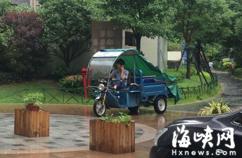 這名快遞哥騎行在小區(qū)通道內(nèi)，一邊接打手機(jī)，一邊還把腳架在車前欄桿上